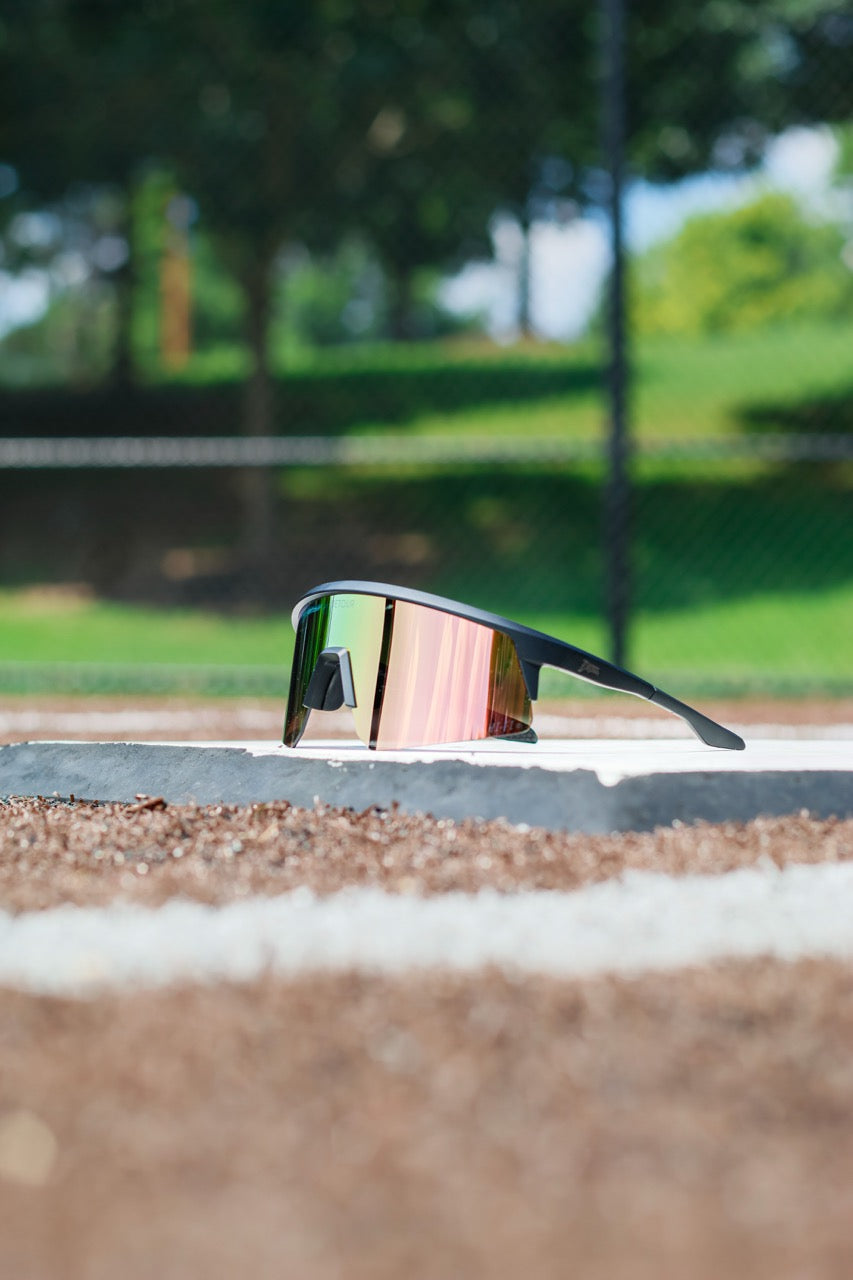 Man wearing mirrored goggles and gray beanie, holding skis in a snowy setting.